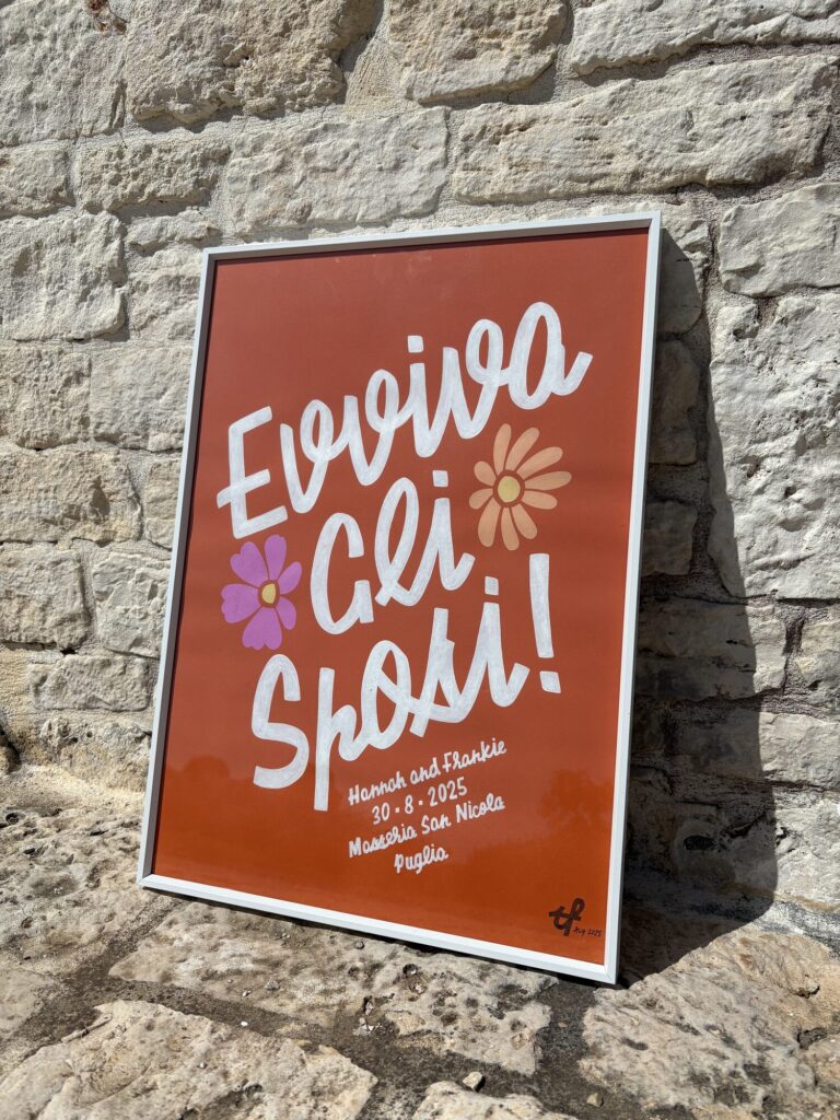 Framed Evviva gli Sposi hand-lettered wedding print against a stone wall
