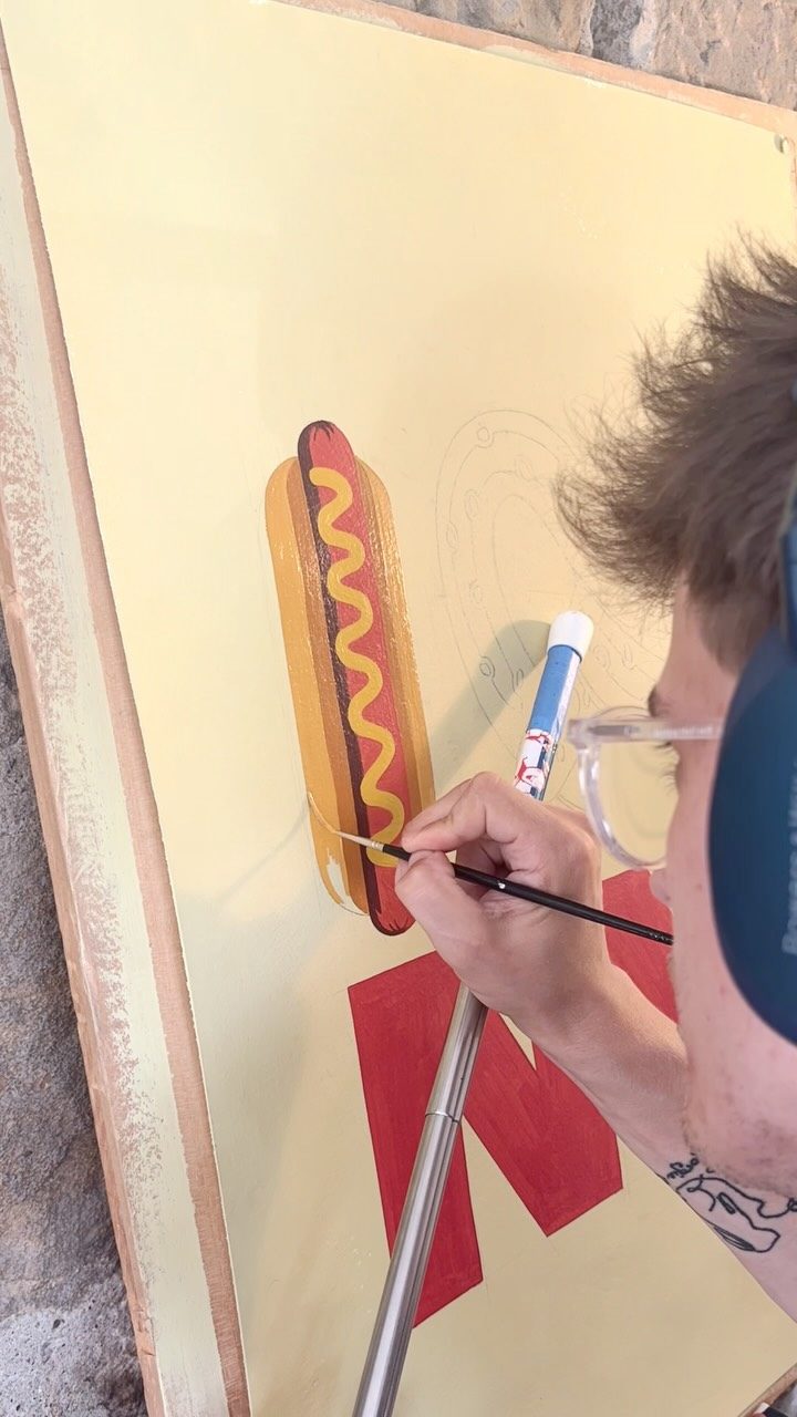 Close-up of a brush painting a hot dog illustration
