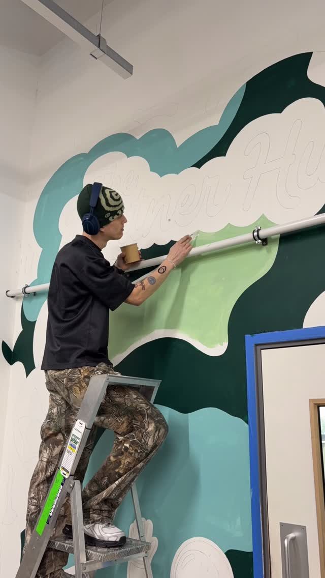 Torin on a step ladder painting a large green and teal office mural Torin on a step ladder painting a large green and teal office mural
