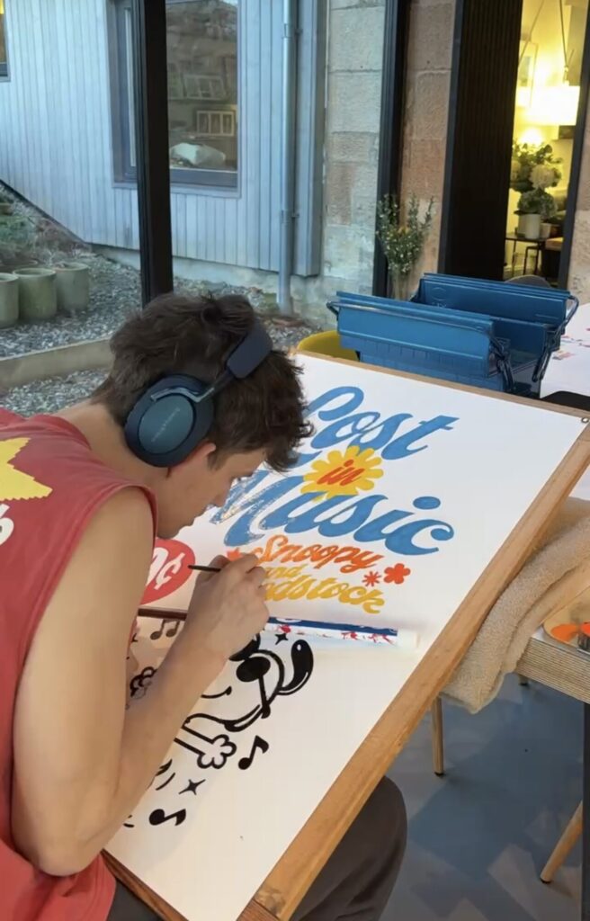 Torin painting the Lost in Music Snoopy poster at his desk