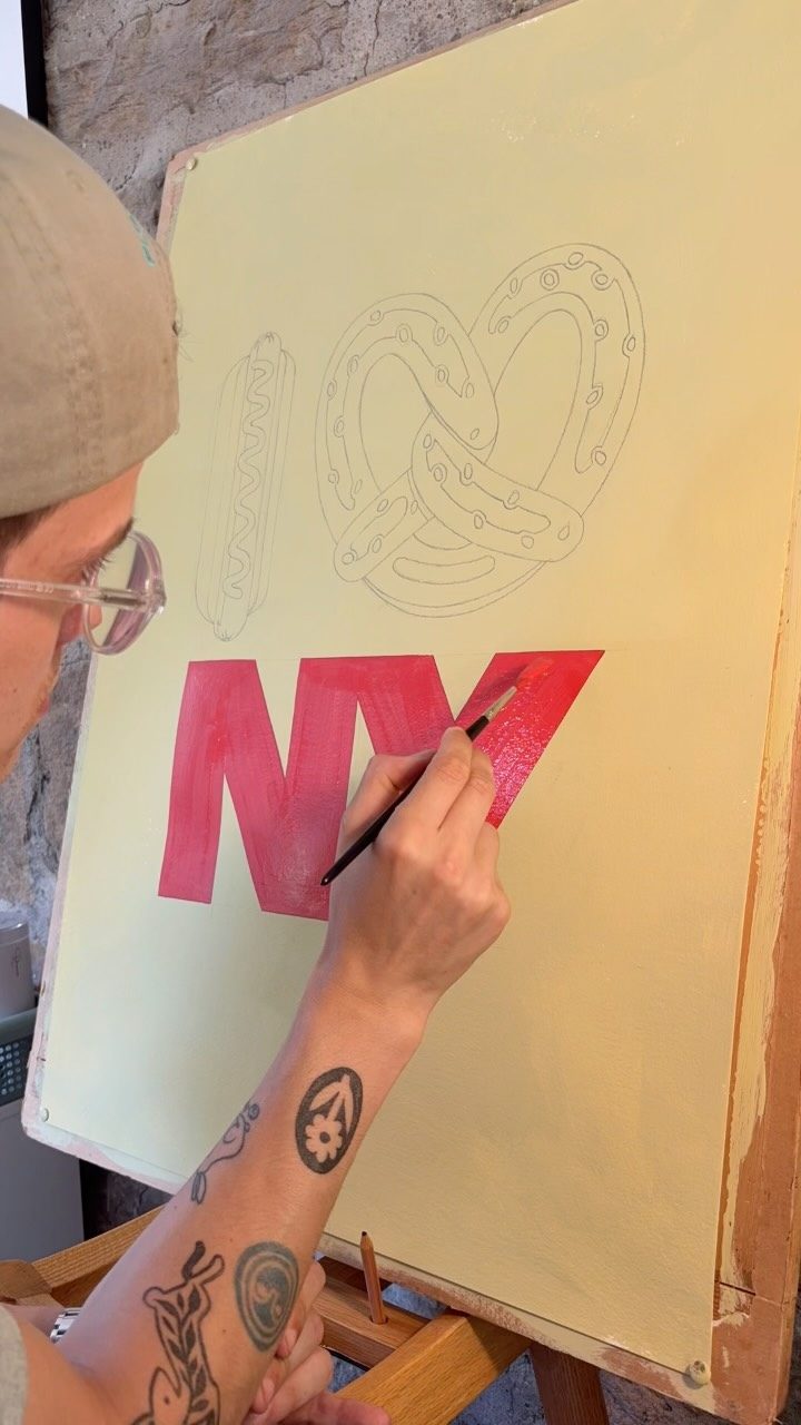 Torin painting large red NY letters on a cream board
