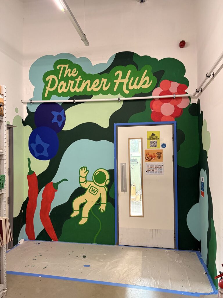 Finished Partner Hub mural with green foliage, berries and an astronaut around an office door