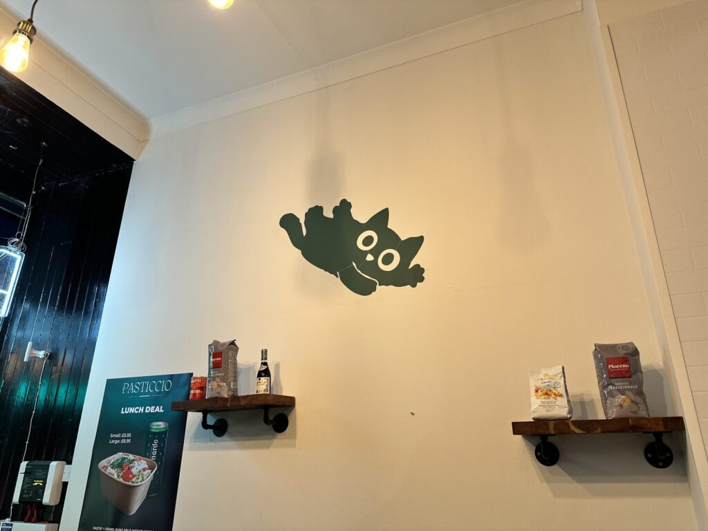 Small painted green cat leaping across the Pasticcio wall
