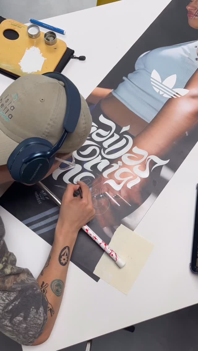 Torin hand-lettering white blackletter script onto a poster