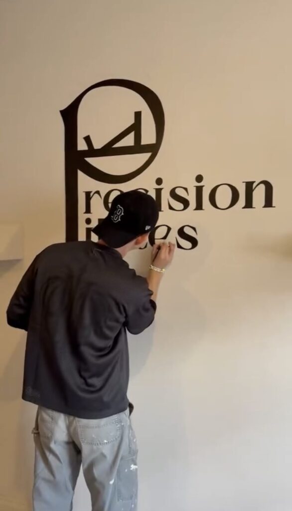 Torin hand-painting the Precision Pilates logo onto a wall