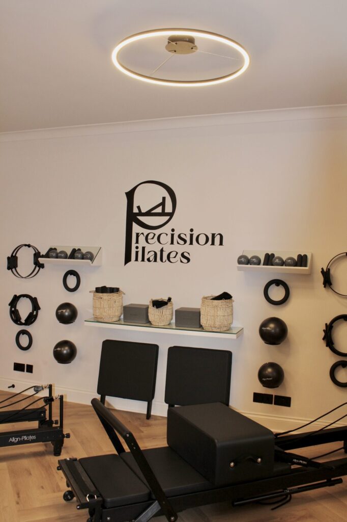 Precision Pilates logo hand-painted on a studio wall above the reformers
