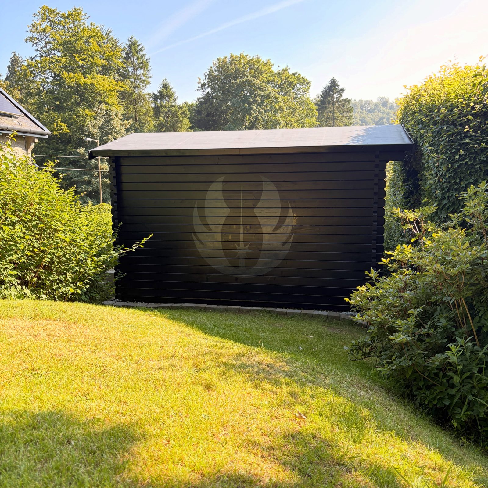 Black garden building with a large painted emblem on its side